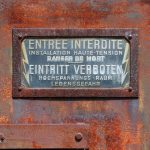 Verrostetes zweisprachiges Emaille-Verbotenschild an einer Trafostation.