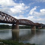 Fachwerk-Eisenbahnbrücke über den Rhein, Bogen, graublauer Himmel, der Fluss. Rostbraun