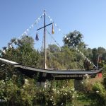 Schlankes, schwarzes Schiff mit Mast und Fähnchen, aufgestellt im Grünen als Dekoration
