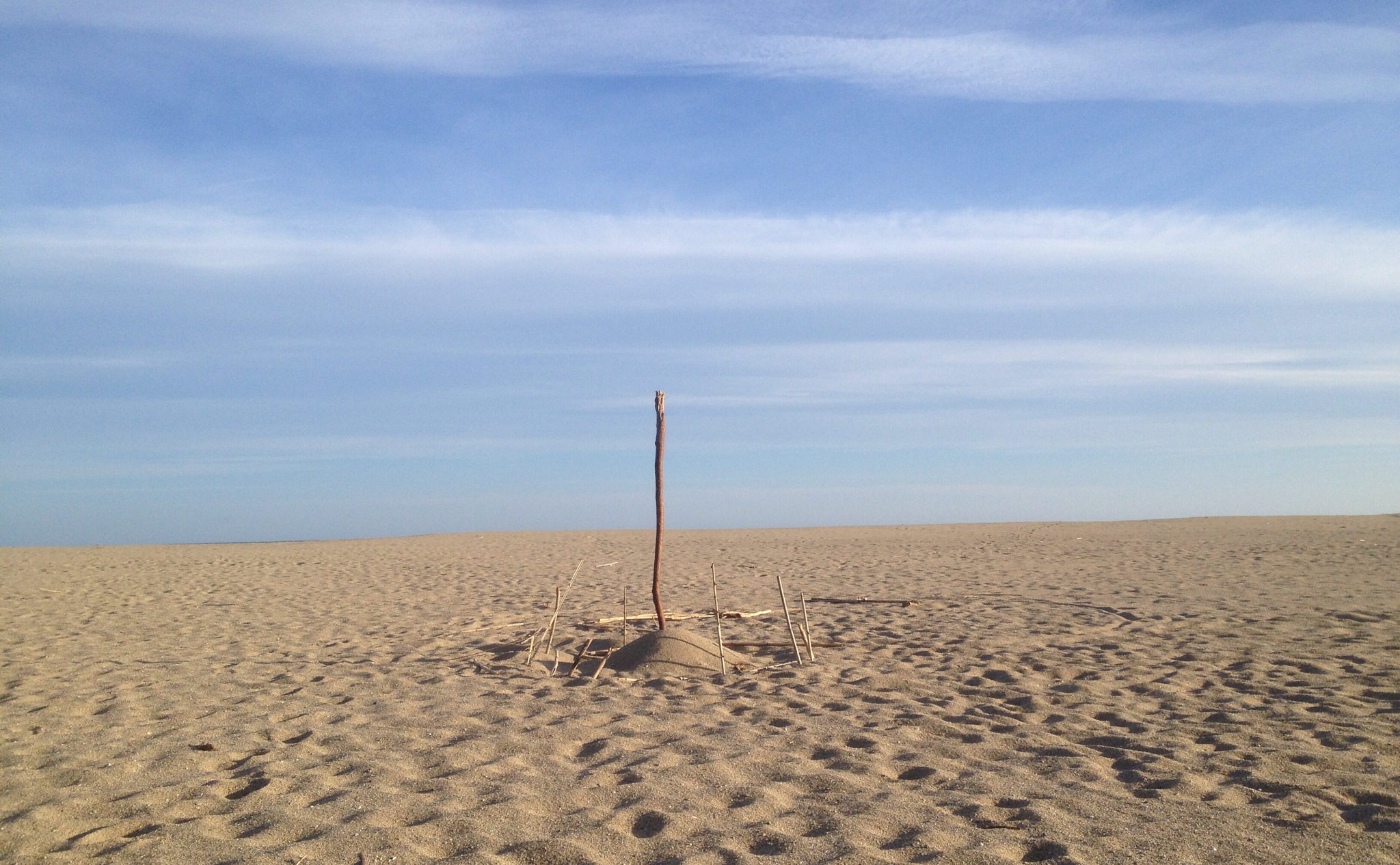 Pfosten auf Sandstrand vor Meer.