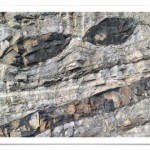 Screenshot einer Postkarte zeigt eine Felswand mit zwei unheimlichen schwarzen Augen, die sich offenbar als Magmaströme in den Gesteinsschichten ausprägten.