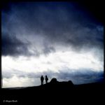 Silhouette zweier Wandererinnen vor Wolkenbehangenem Himmel
