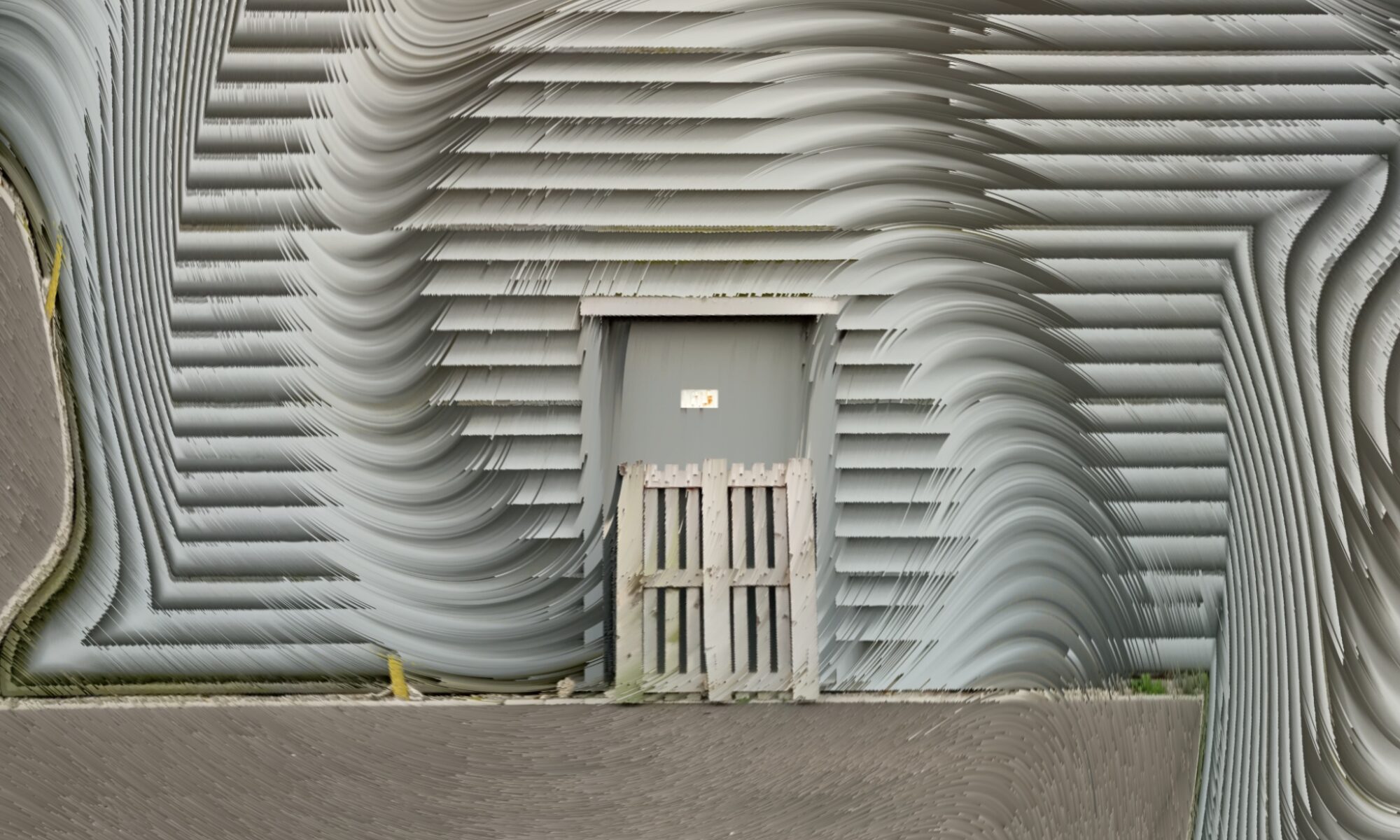Monochromes, fast schwarz-weißes Foto einer Wellblechwand in einem Industriegelände. Eine Tür in der Wand ist mit einer Europalette verstellt. Die Wellblechwand ist von einem digitalen Welleneffekt überblendet und wirkt rechts und links der verbauten Tür wie zwei abstrakte, geriffelte Elefantenfüße.